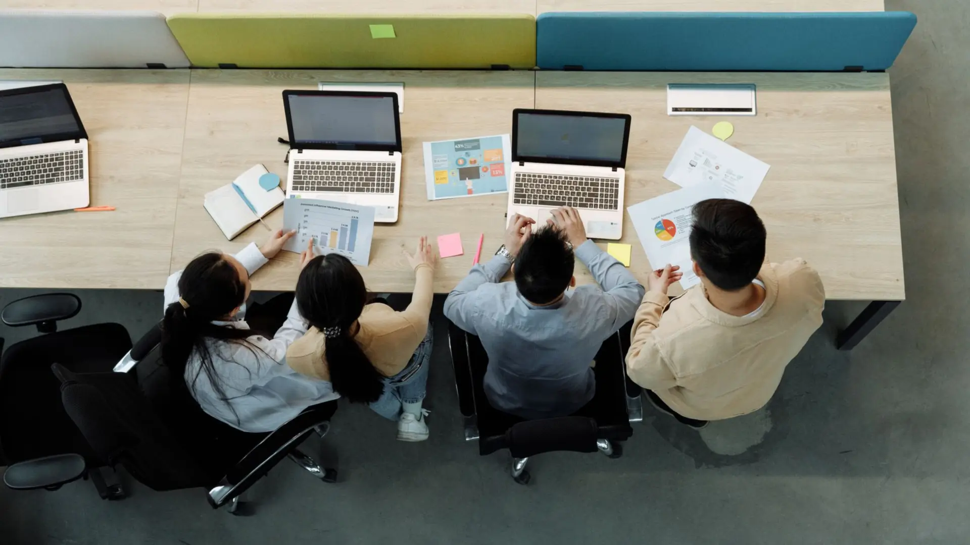 Consultants working together around a table of laptops and documents